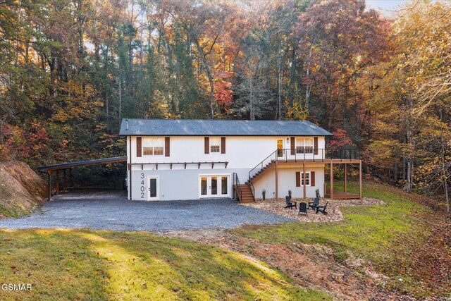 exterior space with a carport, a deck, a lawn, and french doors