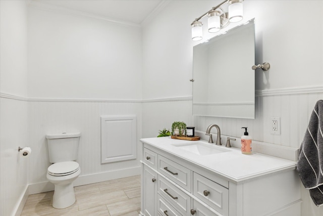 bathroom with toilet, vanity, and ornamental molding