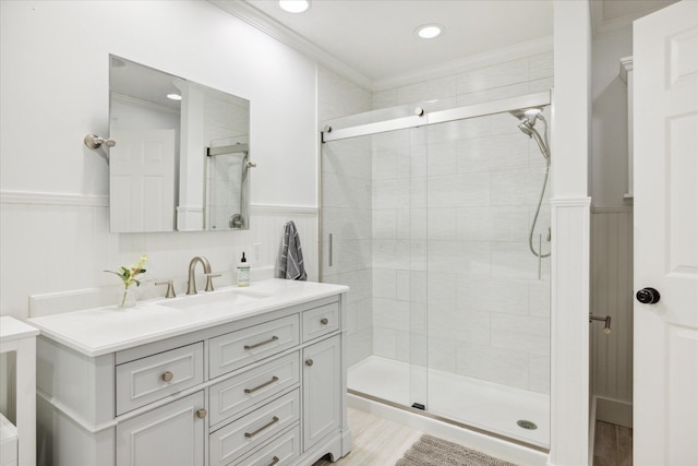 bathroom with vanity, a shower with shower door, and ornamental molding