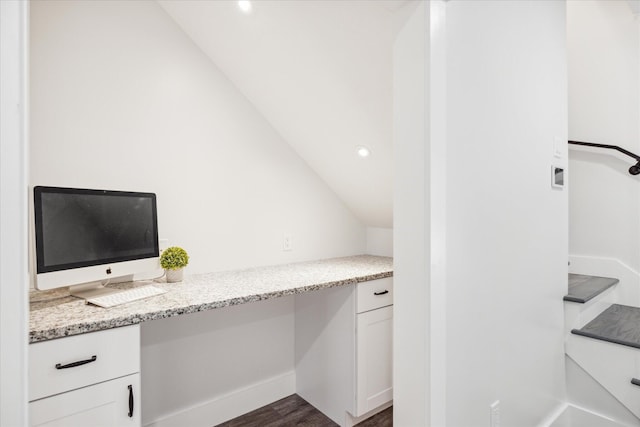 unfurnished office featuring dark hardwood / wood-style flooring, built in desk, and lofted ceiling