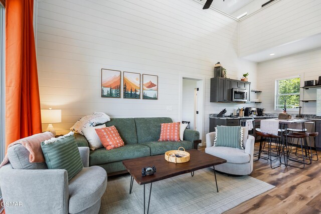 living room with hardwood / wood-style flooring, ceiling fan, and a towering ceiling