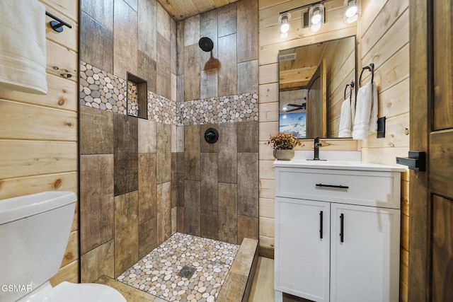 bathroom with a tile shower, wooden walls, and toilet