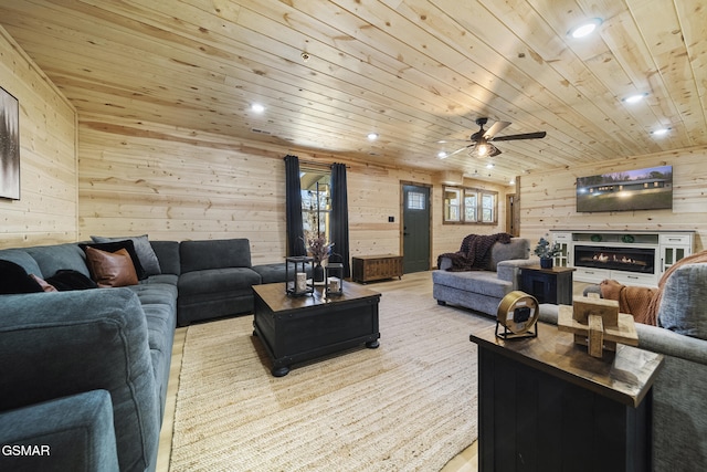 living area with recessed lighting, a glass covered fireplace, wood walls, and wood ceiling