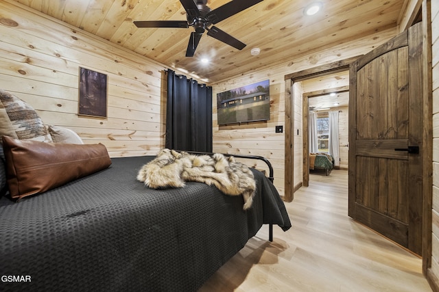 bedroom featuring wood walls, wood ceiling, light wood-style floors, and a ceiling fan