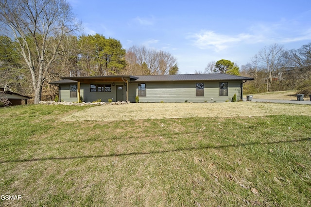 rear view of house featuring a lawn and metal roof