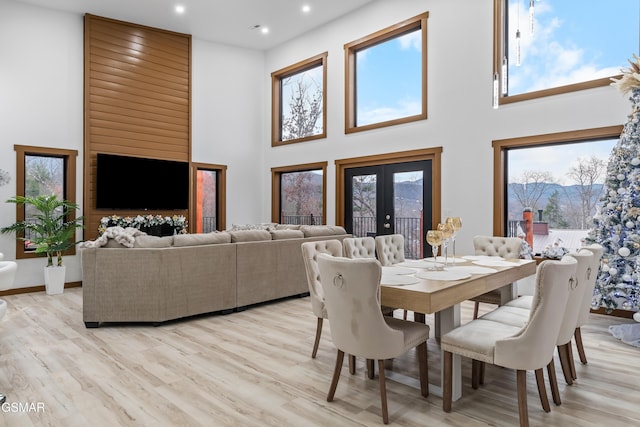 dining space with french doors, light hardwood / wood-style flooring, and a high ceiling