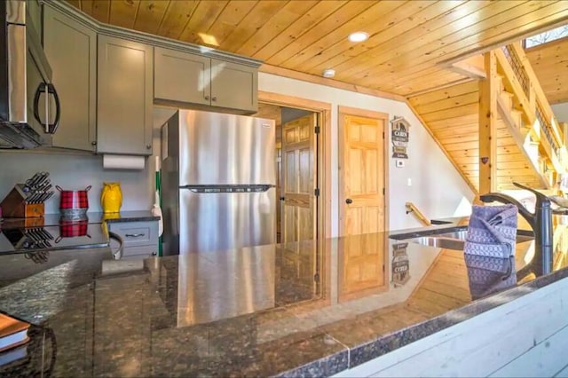 kitchen with dark stone counters, wood ceiling, appliances with stainless steel finishes, and vaulted ceiling