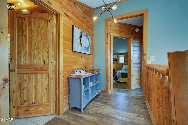 hallway featuring wood walls, an inviting chandelier, and wood finished floors