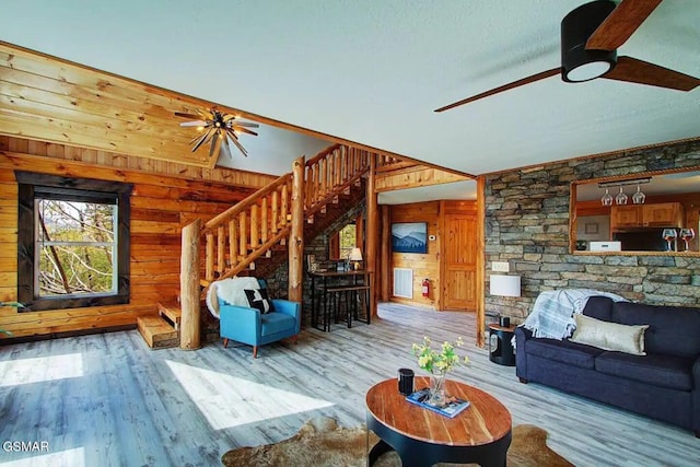 living area with stairway, wood finished floors, ceiling fan, and wood walls