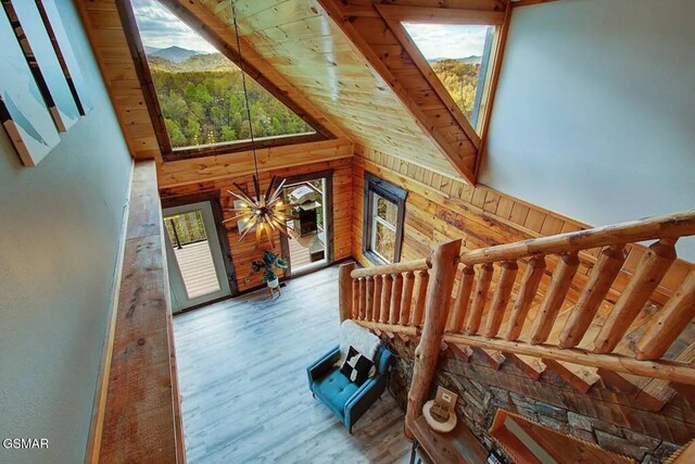 staircase featuring wood ceiling, wood finished floors, wood walls, and high vaulted ceiling