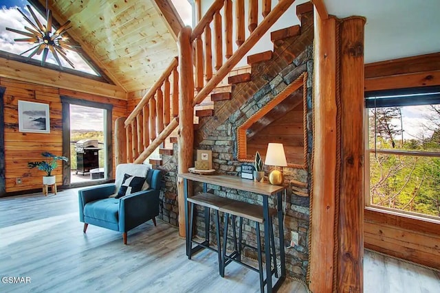 living area with stairway, wooden walls, and wood finished floors