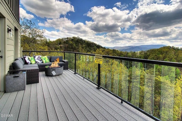 deck with a forest view and an outdoor living space with a fire pit