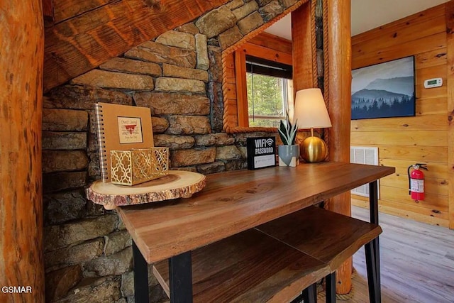 interior space with visible vents, wood walls, wood finished floors, and a fire extinguisher