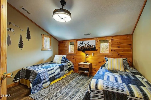 bedroom with vaulted ceiling, wood finished floors, visible vents, and ornamental molding