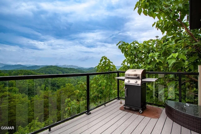 wooden deck with area for grilling, a mountain view, and a forest view