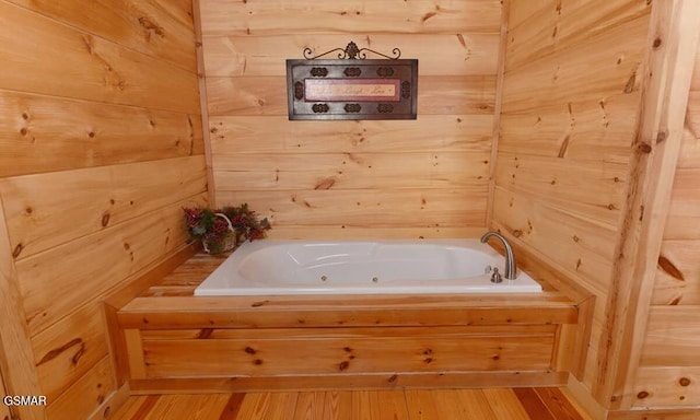 full bathroom featuring wood walls, a whirlpool tub, and wood finished floors