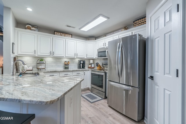 kitchen with white cabinetry, sink, a kitchen bar, and appliances with stainless steel finishes