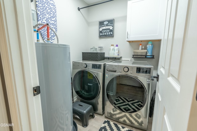 laundry area with cabinets, light hardwood / wood-style floors, and washing machine and dryer