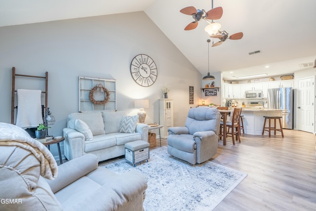 living room featuring high vaulted ceiling, ceiling fan, and light wood-type flooring