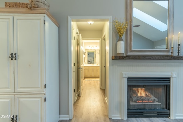 hall featuring lofted ceiling and light hardwood / wood-style flooring