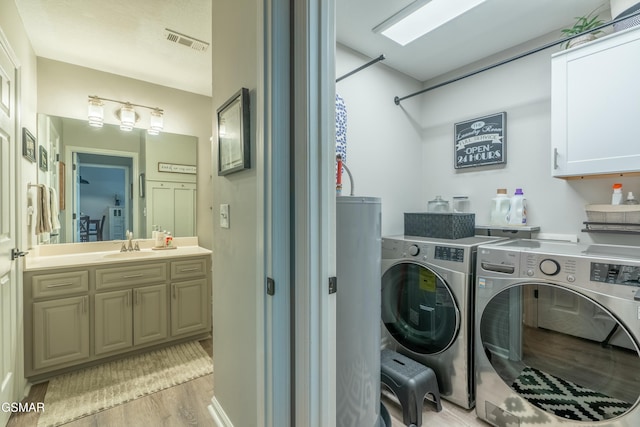 laundry area with sink, washing machine and dryer, and light wood-type flooring