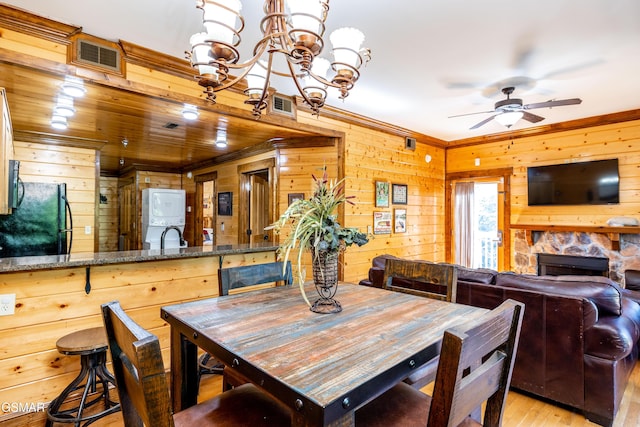 415 Big Bear Way, Pigeon Forge, TN 37863 - dining room featuring wood walls, a ceiling fan, a stone fireplace, a chandelier, and light wood-style flooring