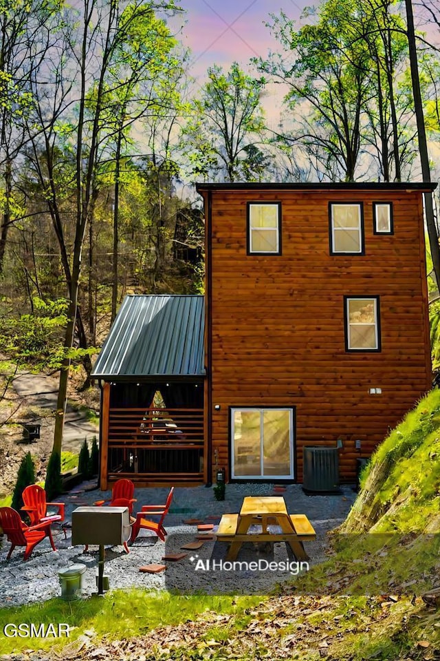 back of house at dusk featuring an outdoor fire pit, a patio area, metal roof, and central AC unit