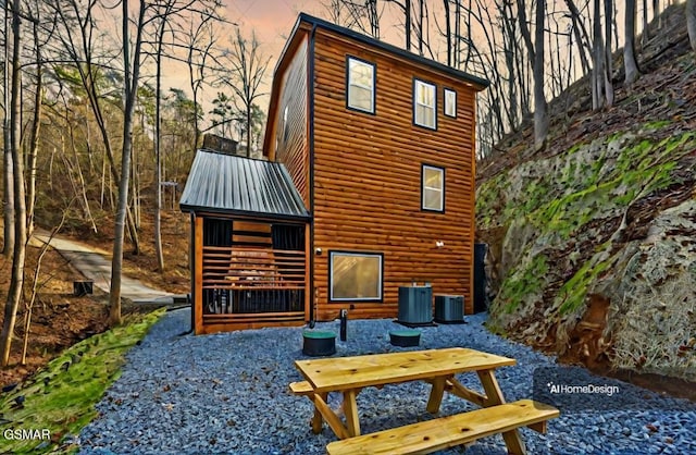 back of property with metal roof, central AC, and log veneer siding