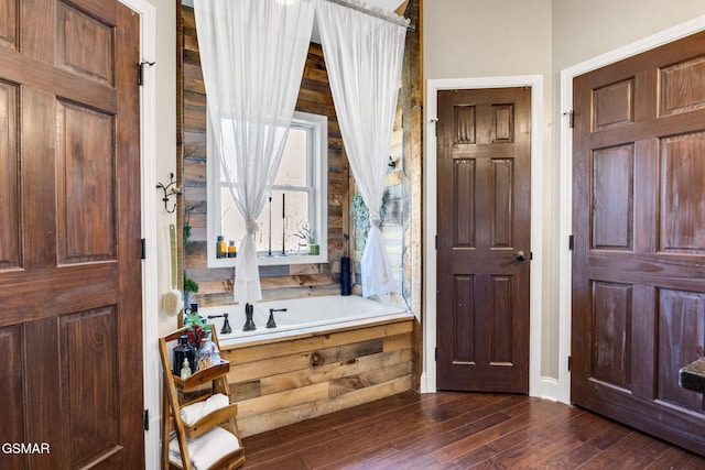 bathroom featuring hardwood / wood-style floors and a tub to relax in