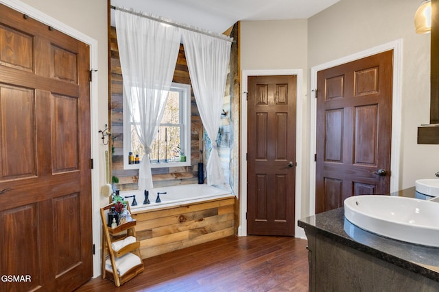 bathroom featuring wood-type flooring, vanity, and a relaxing tiled tub