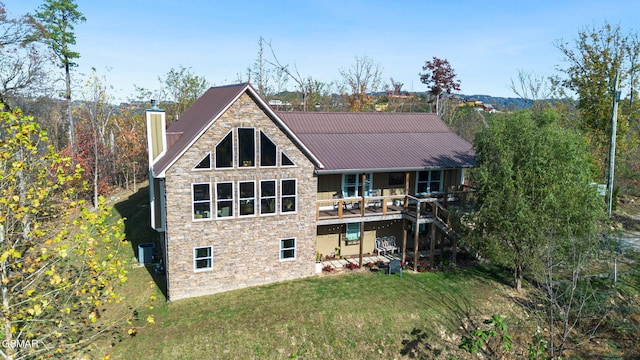 back of property featuring a lawn, cooling unit, and a deck