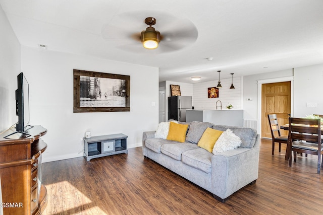 living room with ceiling fan, sink, and dark wood-type flooring