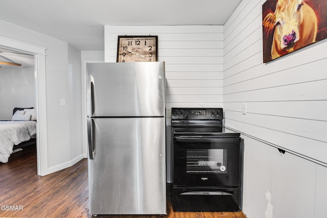 kitchen featuring black range with electric cooktop, dark wood-type flooring, stainless steel refrigerator, and wooden walls