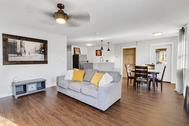 living room featuring ceiling fan and dark wood-type flooring