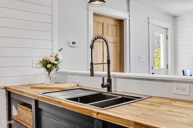 interior details with butcher block countertops, wooden walls, and sink