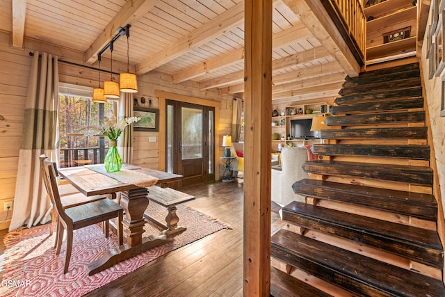 dining area featuring wooden walls, hardwood / wood-style flooring, wood ceiling, stairway, and beamed ceiling