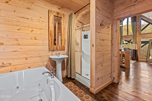 bathroom featuring wood walls, wood finished floors, a wealth of natural light, and a stall shower