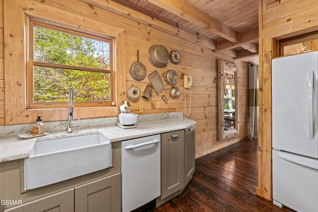 kitchen with gray cabinets, a sink, freestanding refrigerator, and wooden walls