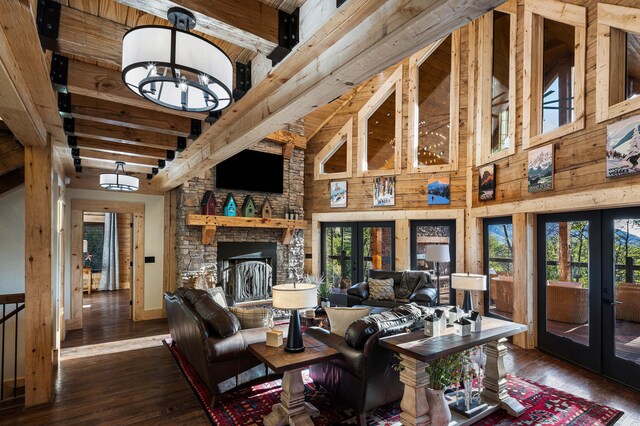 living room featuring french doors, a towering ceiling, a chandelier, dark hardwood / wood-style floors, and wood walls