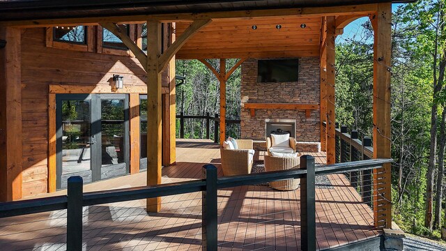 wooden deck with an outdoor stone fireplace and french doors