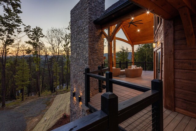 deck at dusk featuring ceiling fan and an outdoor hangout area