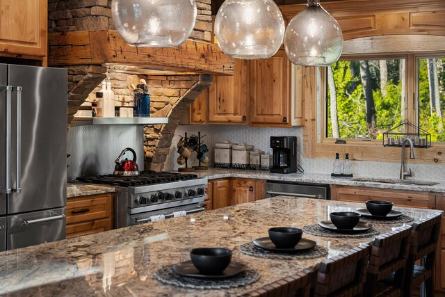 kitchen featuring light stone countertops, sink, hanging light fixtures, decorative backsplash, and high end appliances