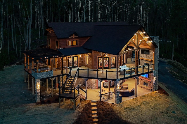 rear view of house with an outdoor living space with a fireplace and a patio