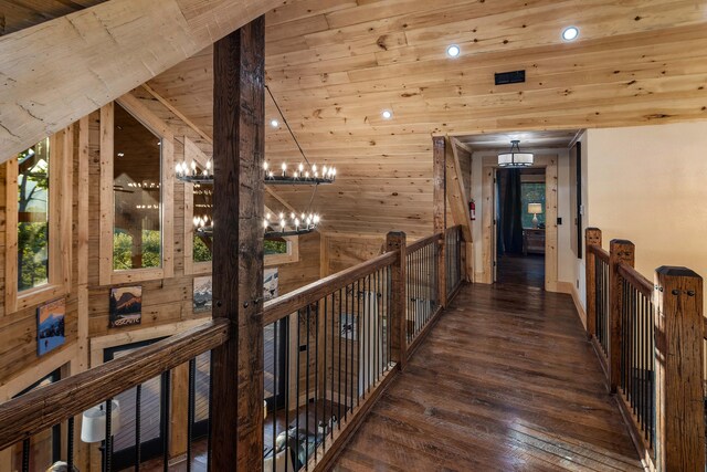 hallway with wood walls, wooden ceiling, dark wood-type flooring, an inviting chandelier, and vaulted ceiling