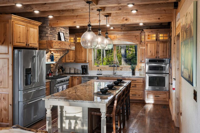 kitchen featuring light stone countertops, appliances with stainless steel finishes, a breakfast bar, a kitchen island, and hanging light fixtures