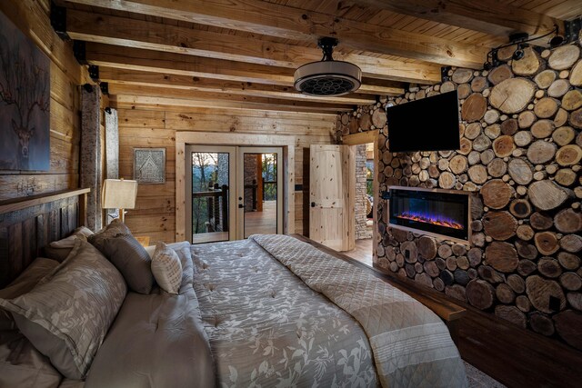 bedroom with wood walls, beam ceiling, a stone fireplace, and wooden ceiling