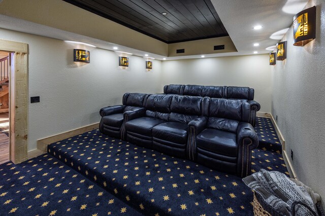 cinema room with carpet flooring, a raised ceiling, and wooden ceiling