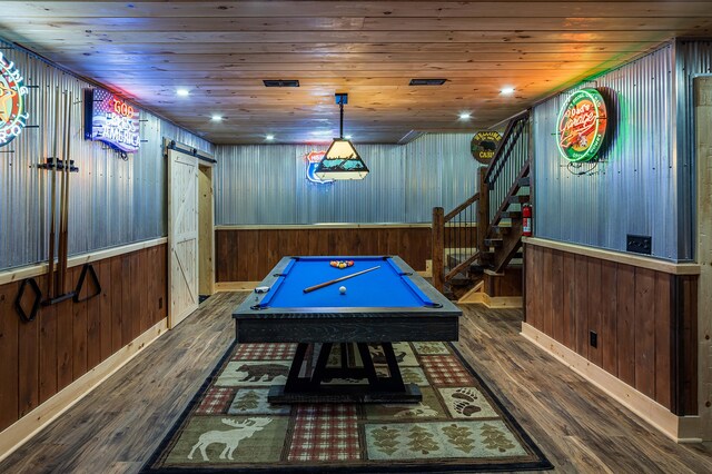 playroom featuring a barn door, dark hardwood / wood-style floors, wooden walls, and billiards