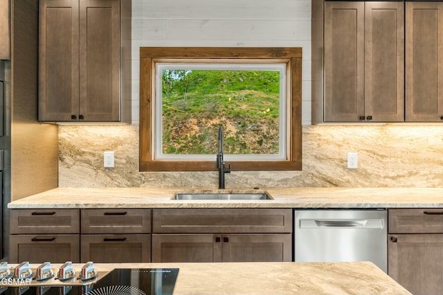 kitchen with light stone countertops, backsplash, stainless steel dishwasher, and a sink