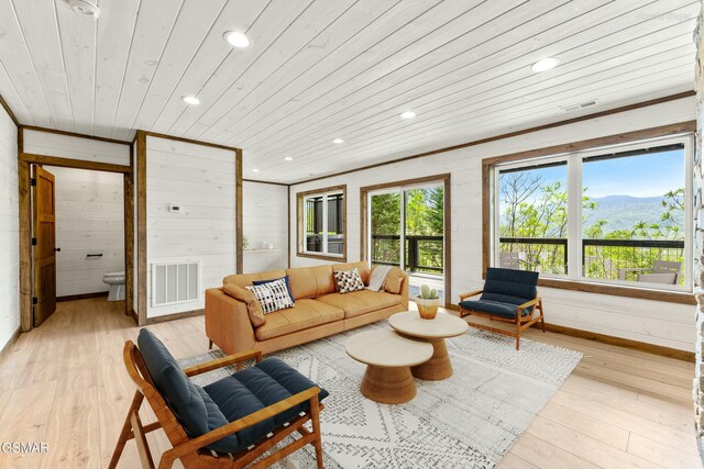 living room featuring visible vents, light wood-type flooring, and wood ceiling